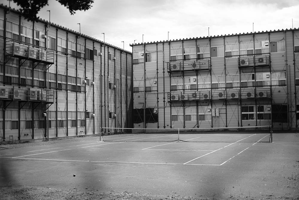 高校の仮設校舎とその間にあるテニスコート。